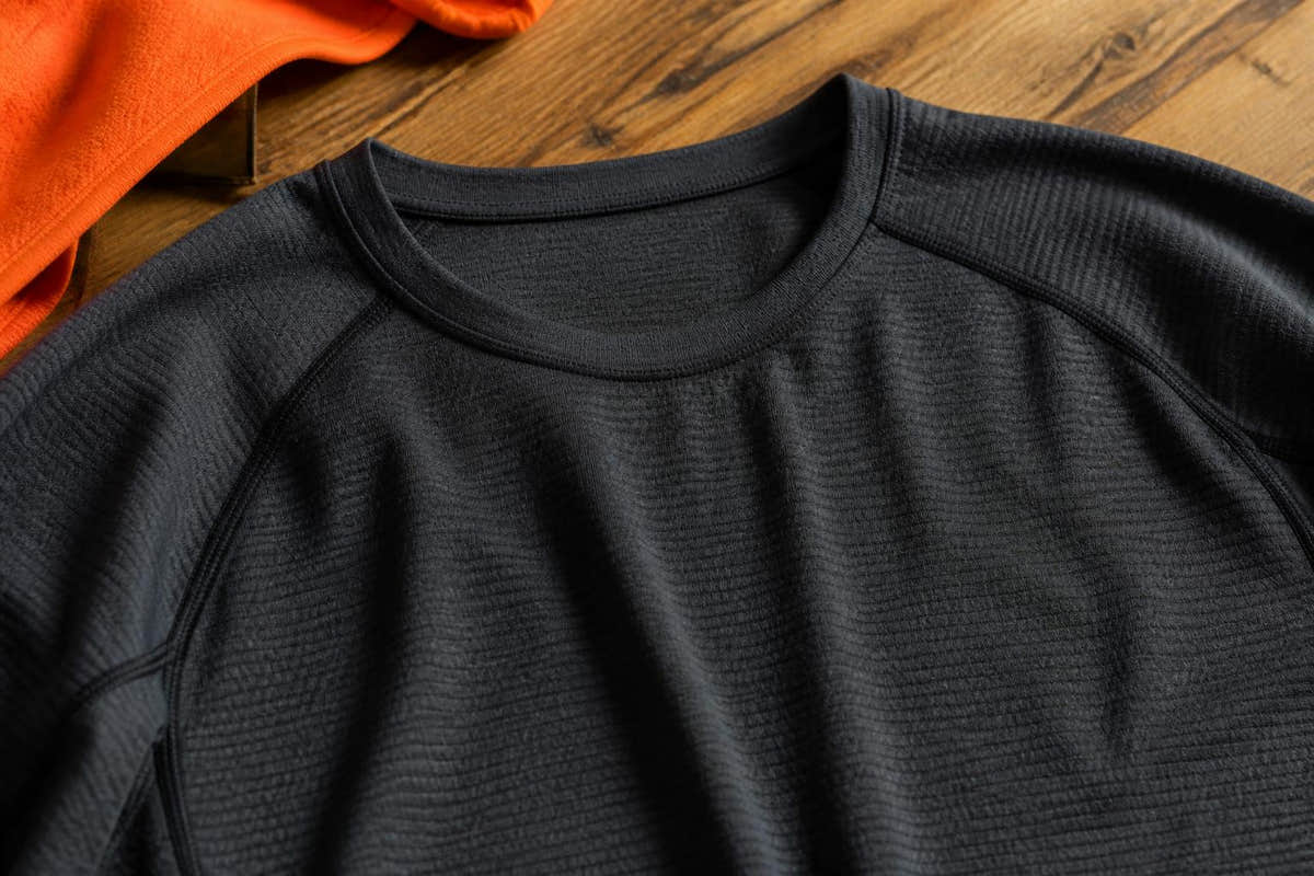 Close-up of a person wearing a fitted, long-sleeved thermal base layer under a structured work shirt